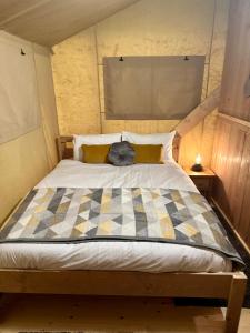 a bedroom with a bed with a checkered blanket on it at Cherry Tree Safari Lodge in Talaton