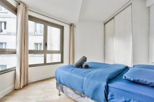 a bedroom with a blue bed and a large window at Appartement Quartier Republique in Paris