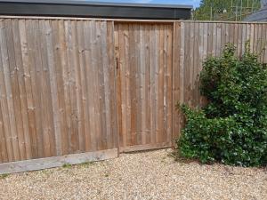 a wooden fence with a bush in front of it at The Old Garage in West Itchenor