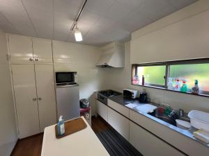 a small kitchen with a sink and a refrigerator at Den House in Oshima