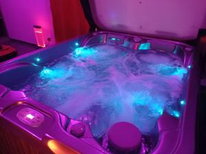 bañera de hidromasaje con luces azules y moradas en una habitación en Paradis Secret Spa en Damprichard