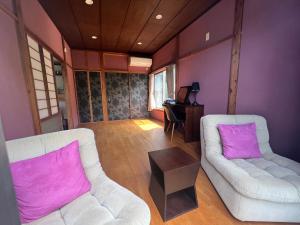 sala de estar con 2 sillas blancas y paredes moradas en Den House, en Oshima