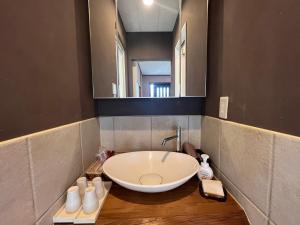 baño con lavabo grande y espejo en Den House, en Oshima