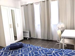 1 dormitorio con cama azul, mesa y ventanas en *Promo!* 2-Min to Train Station! en Melbourne