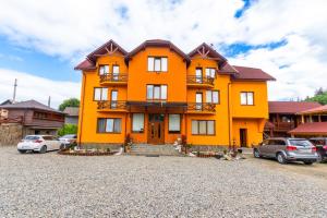 an orange house with cars parked in front of it at У Румуна in Yasinya