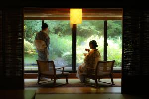um homem e uma mulher olhando pela janela em Tsubaki em Yugawara