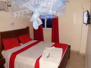 a bedroom with a bed with red curtains and a window at Hotel Basilea Mtwapa in Mtwapa