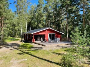 a red cabin with a deck in the woods at Säilöksen Lomahuvilat in Luhanka