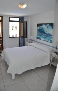 1 dormitorio con cama blanca y ventana en Sobre el Mar en Edificio Magallanes, en El Médano