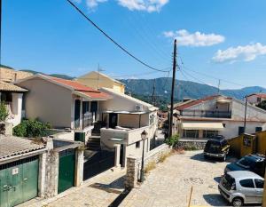 un groupe de maisons avec des voitures garées dans un parking dans l'établissement Traditional Detached Corfu House, 50m to village square, à Liapades