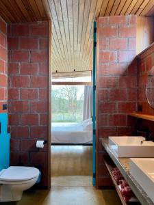 - une salle de bains aux murs de briques pourvue de toilettes et d'un lit dans l'établissement rodune, à Coxyde