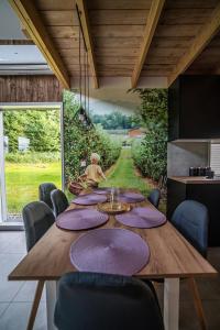 jadalnia z dużym drewnianym stołem i fioletowymi serwetkami w obiekcie Łąckie Zacisze w Łącku