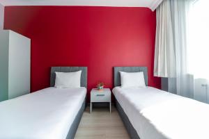 two beds in a room with a red wall at Hexa Suites Hotel in Istanbul