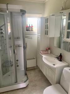 a white bathroom with a shower and a sink at Ruim en licht familiehuis No 21 in Föllinge
