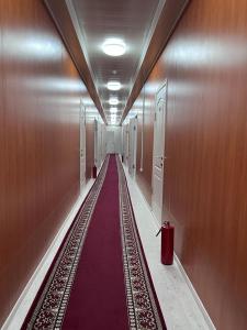 Bal-Meyir Hotel في ألماتي: ممر طويل مع سجادة حمراء في مبنى