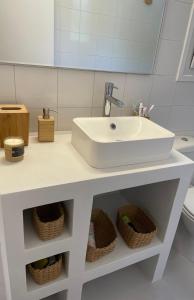 a bathroom with a white sink and baskets at VIlla Gorgona, maison cycladique in Gavrion