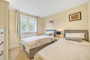 a bedroom with two beds and a window at Country cottage & Tennis court in Warnham