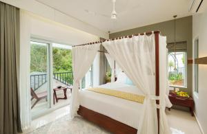 a bedroom with a canopy bed and a balcony at Eden Woods Resorts and Spa in Munnar