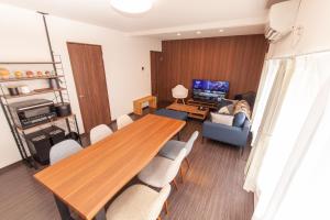 ツナゲル青森安方Villa Suite في أوموري: غرفة معيشة مع طاولة وكراسي خشبية كبيرة
