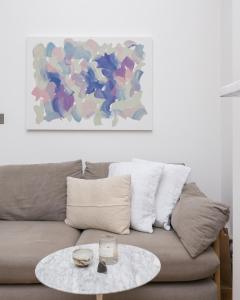 a coffee table in front of a couch with a painting at Light filled studio with view of Regents Park in London