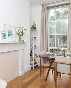 a dining room with a table and a fireplace at Light filled studio with view of Regents Park in London
