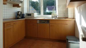 eine Küche mit Holzschränken, einem Waschbecken und einem Fenster in der Unterkunft Haus Holstein Meinke WE 13 W-LAN in Ostseebad Sellin