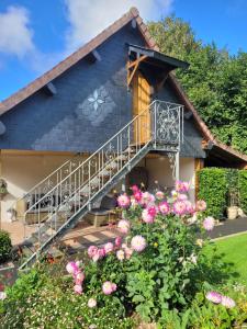 a house with a staircase and flowers at Au chant des oiseaux in Le Torquesne