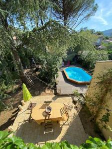 einen Blick über eine Terrasse mit einem Tisch und einem Pool in der Unterkunft Pavillon dans un écrin de verdure avec piscine in Lodève
