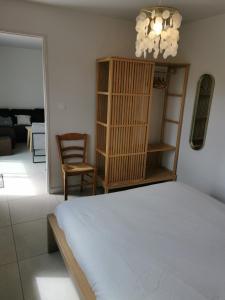 ein Schlafzimmer mit einem Bett, einem Stuhl und einem Kronleuchter in der Unterkunft Gîte La Coumette - classé 3 étoiles in Crampagna