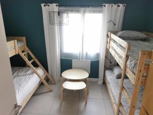 1 Schlafzimmer mit 2 Etagenbetten, einem Tisch und einem Stuhl in der Unterkunft Gîte La Coumette - classé 3 étoiles in Crampagna