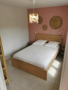 Schlafzimmer mit einem Bett mit weißer Bettwäsche und einem Kronleuchter in der Unterkunft Gîte La Coumette - classé 3 étoiles in Crampagna
