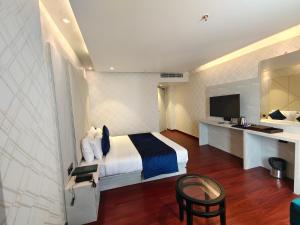 Habitación de hotel con cama, escritorio y TV. en The Emerald Hotel & Siya Milan Banquets en Muzaffarpur