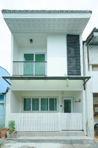 a white house with a balcony on top of it at Nut Home Hostel in Ban Ko
