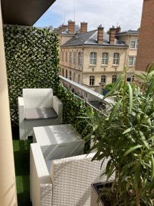 uma varanda com mobiliário branco e algumas plantas e edifícios em Paris 42m Studio plus terrace em Paris