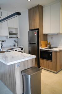 La cuisine est équipée d'un réfrigérateur en acier inoxydable et de placards blancs. dans l'établissement Modern & Minimalist 2-Bedroom Apartment in PJ, à Petaling Jaya