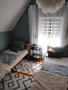 Cette chambre mansardée comprend 2 lits et une fenêtre. dans l'établissement Domek letniskowy "Pod dębem", à Urowo