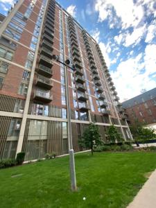 ein hohes Gebäude mit grünem Rasen davor in der Unterkunft 3 bed luxury spacious apartment with pool in Manchester