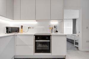 cocina blanca con armarios blancos y horno en 3 bed luxury spacious apartment with pool, en Mánchester