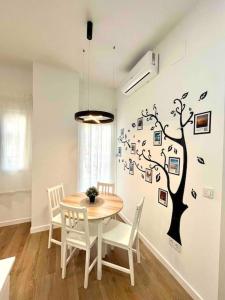 une salle à manger avec une table et un arbre sur le mur dans l'établissement Acogedor apartamento 5 personas, à Valence