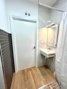 Acogedor apartamento 5 personas في فالنسيا: حمام فيه باب أبيض ومغسلة