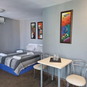 モンタナにあるХотел Европаのベッド、テーブル、椅子が備わる客室です。