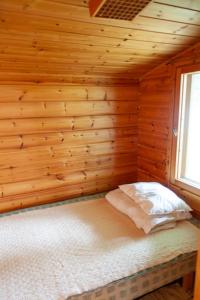 ein Schlafzimmer mit einem Bett in einer Holzwand in der Unterkunft Katriina, huom! sijaitsee saaressa, locates on island in Tahkovuori