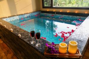 ein Pool mit zwei Gläsern Wein und ein Tablett mit Kerzen in der Unterkunft Niyatma Wayanad Pool Resort by VOYE HOMES - Inside Coffee Plantation in Wayanad