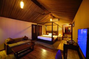a bedroom with a bed and a couch and a tv at Niyatma Wayanad Premium Coffee Resort By VOYE HOMES in Wayanad