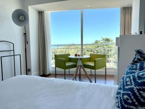 a bedroom with a bed and a table and chairs at Hôtel & Spa Le Grand Large in Dolus-d'Oléron