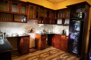 eine Küche mit Holzschränken und einem schwarzen Kühlschrank in der Unterkunft WIMAL PALACE in Jaffna
