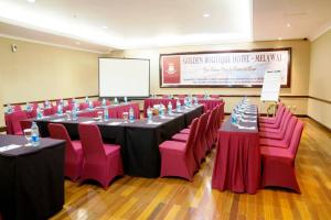 a conference room with long tables and pink chairs at Golden Boutique Hotel Melawai in Jakarta