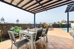 einen weißen Tisch und Stühle auf einer Terrasse mit einem Pool in der Unterkunft Villa Liv in Playa Blanca