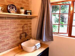 a bathroom with a sink and a brick wall at Modern Industrial Cottage in Kingsburgh