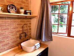 ein Badezimmer mit Waschbecken und einer Ziegelwand in der Unterkunft Modern Industrial Cottage in Kingsborough